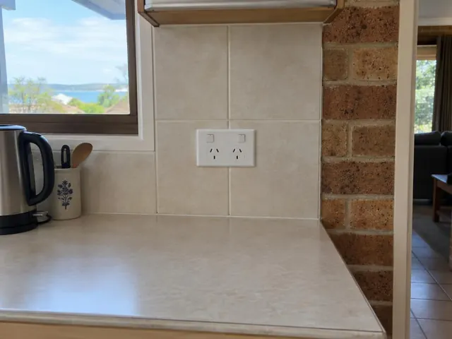 Double power point on tiled kitchen splashback beside a brick wall in a home kitchen in Marks Point